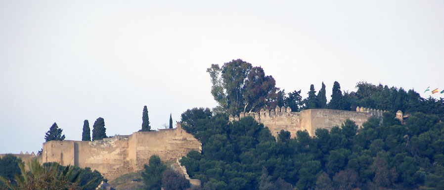 La Alcazaba se une al Castillo de Gibralfaro por su lado noreste a través de un corredor delimitado por muros que se disponen sinuosamente.